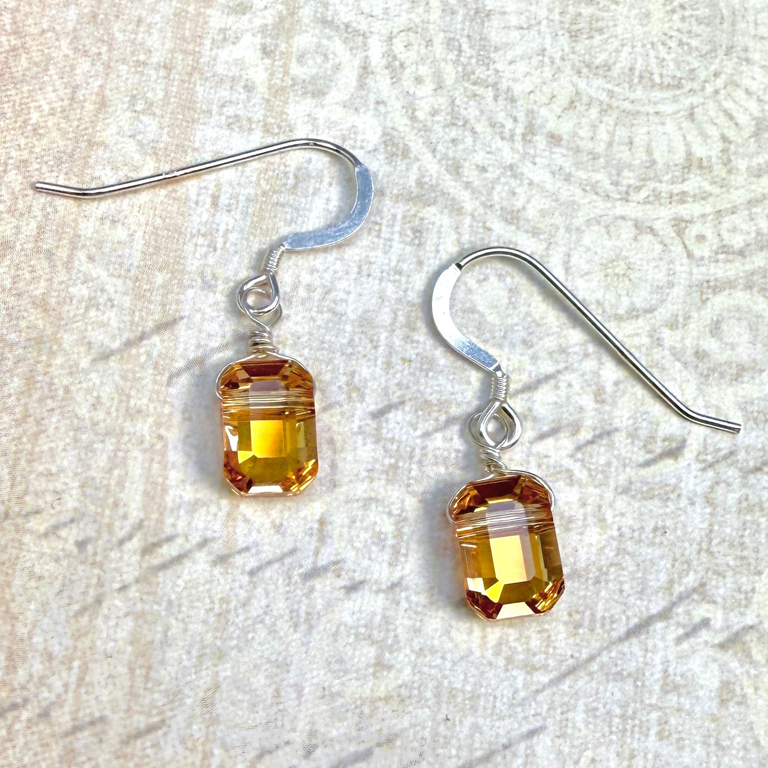 Pair of sunny yellow rectangular crystal earrings on a textured white background with sterling silver hooks