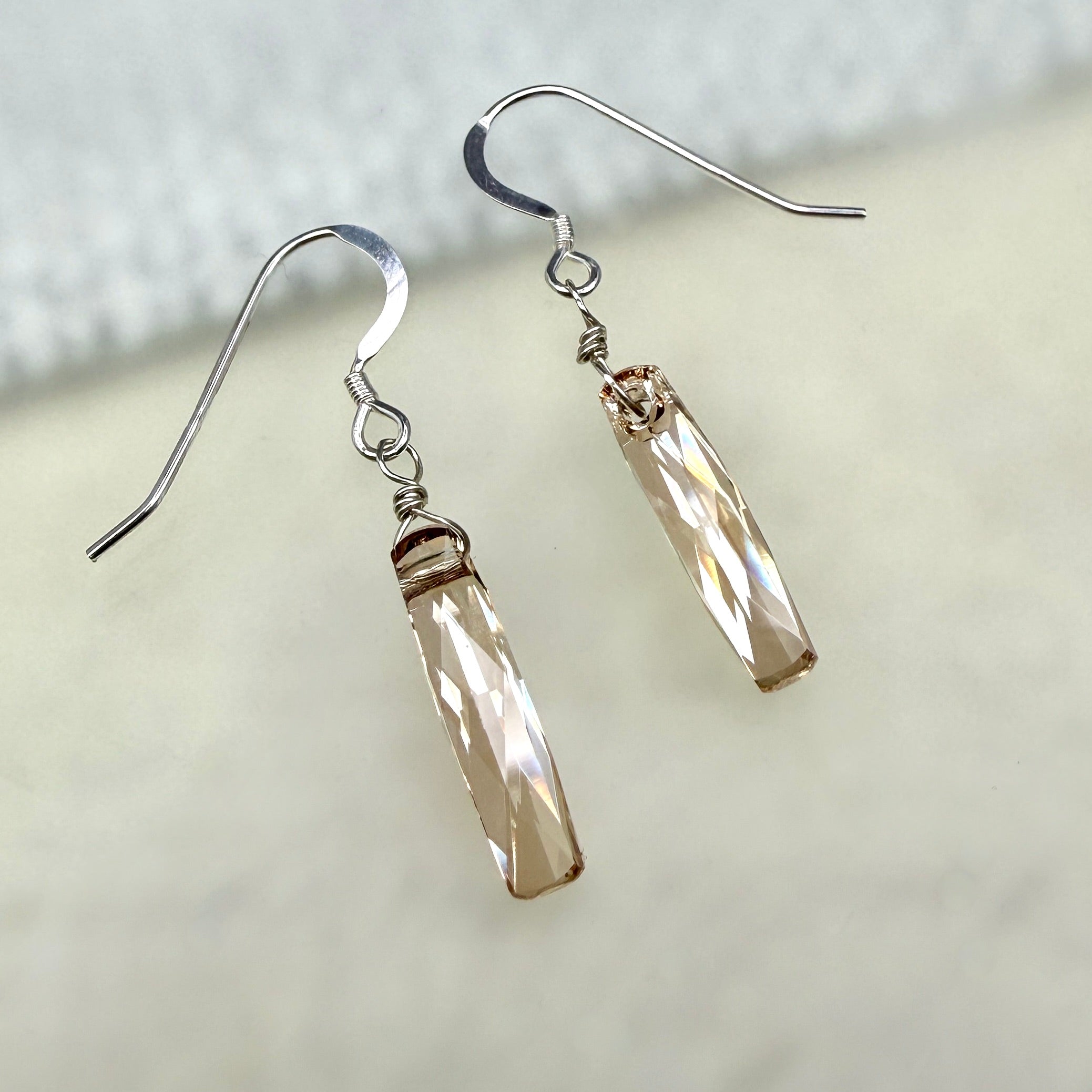 Pair of warm tan crystal earrings on a white and tan background