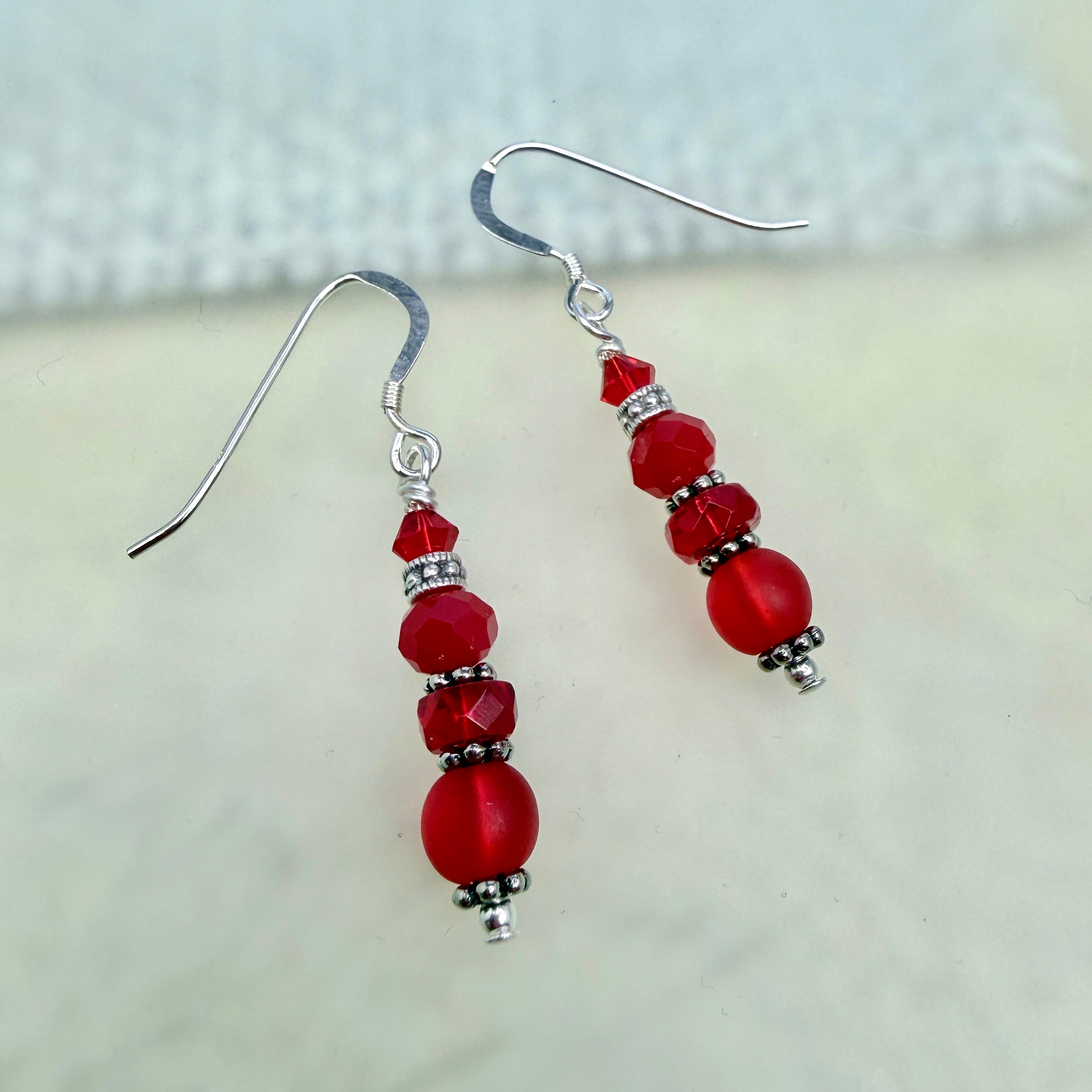 Red beaded earrings with silver hooks on a light background