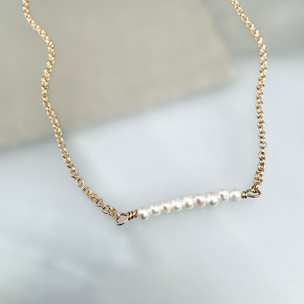 Gold necklace with pearls on a light gray background