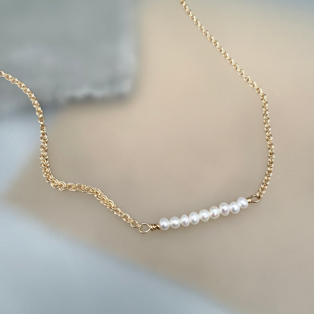 Gold chain necklace with pearls on a soft background