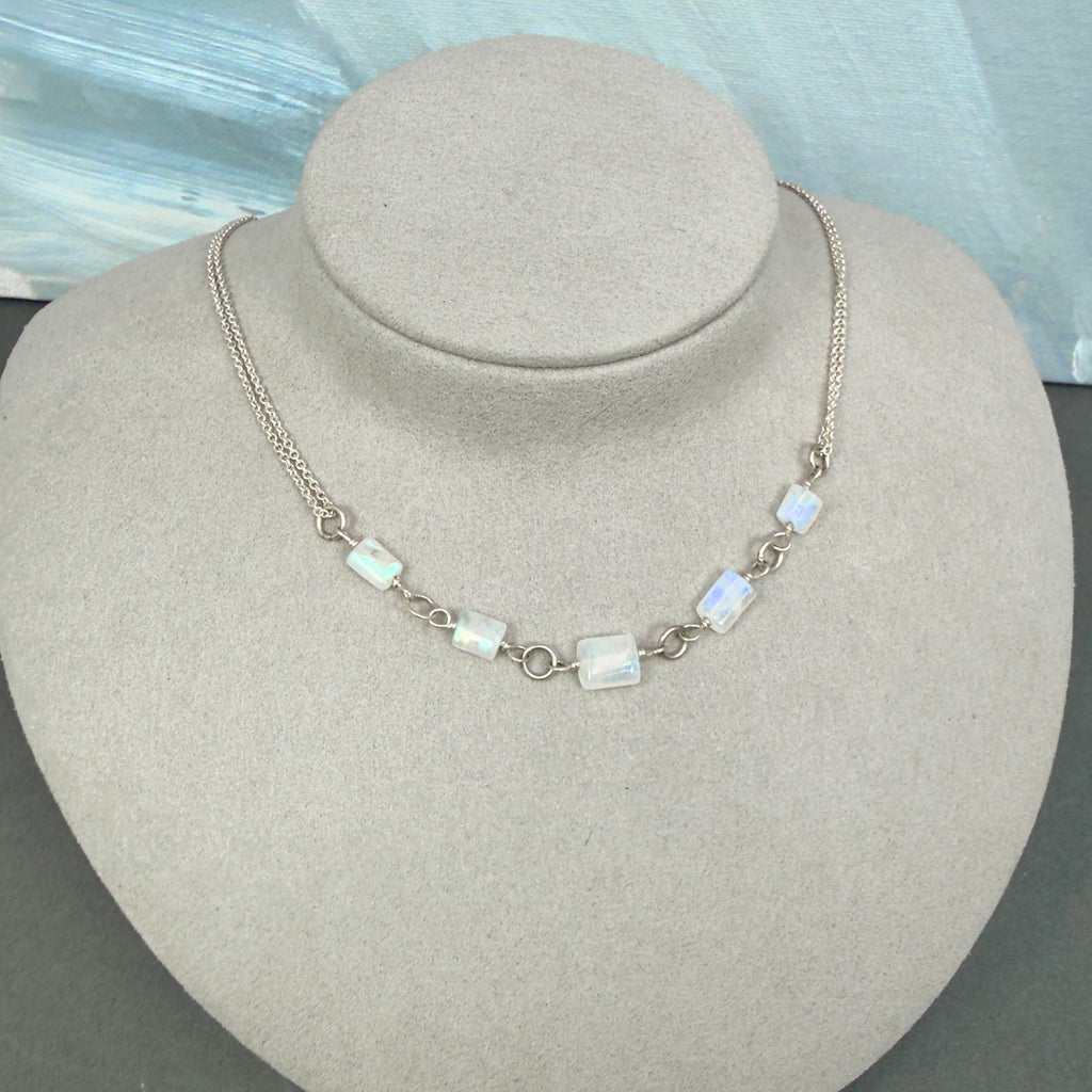 Necklace with rectangular rainbow moonstone beads on a gray bust