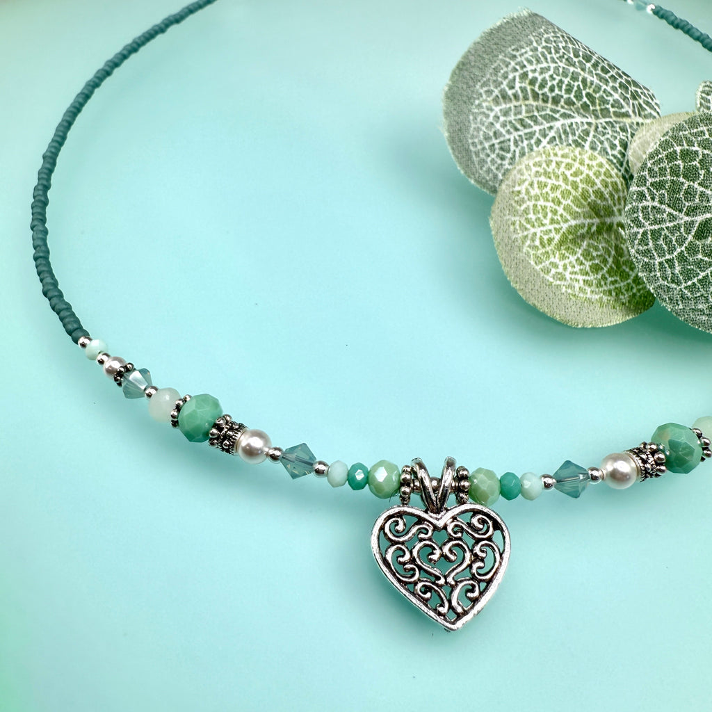 Soft minty green and white with silver accents and a heart pendant on a green background with leaves