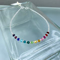 Multicolored beaded anklet on a clear glass background
