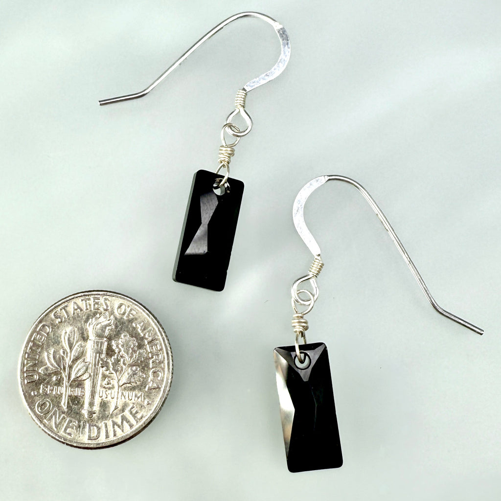 Black rectangular earrings on silver hooks with a dime for scale on a white background