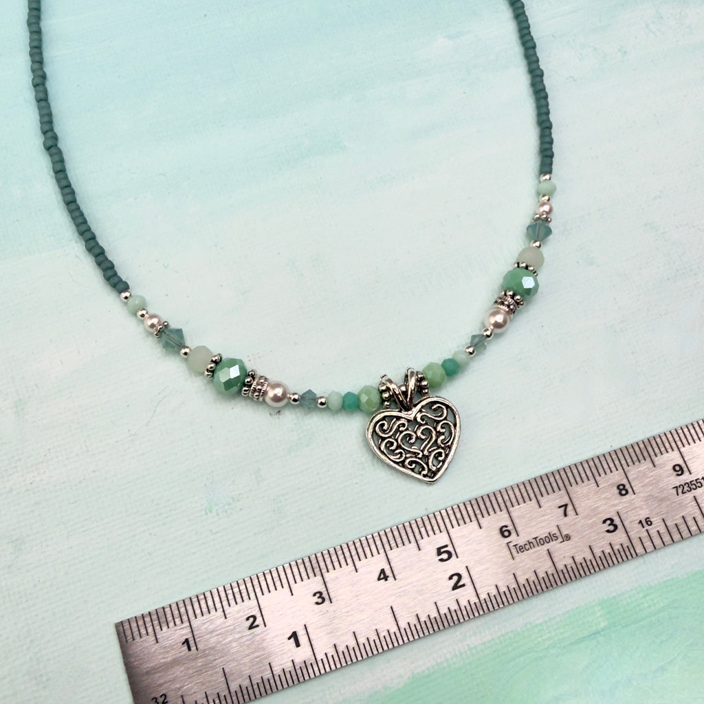 Soft minty green and white with silver accents and a heart pendant on apple green background with a ruler in inches and centimeters for reference
