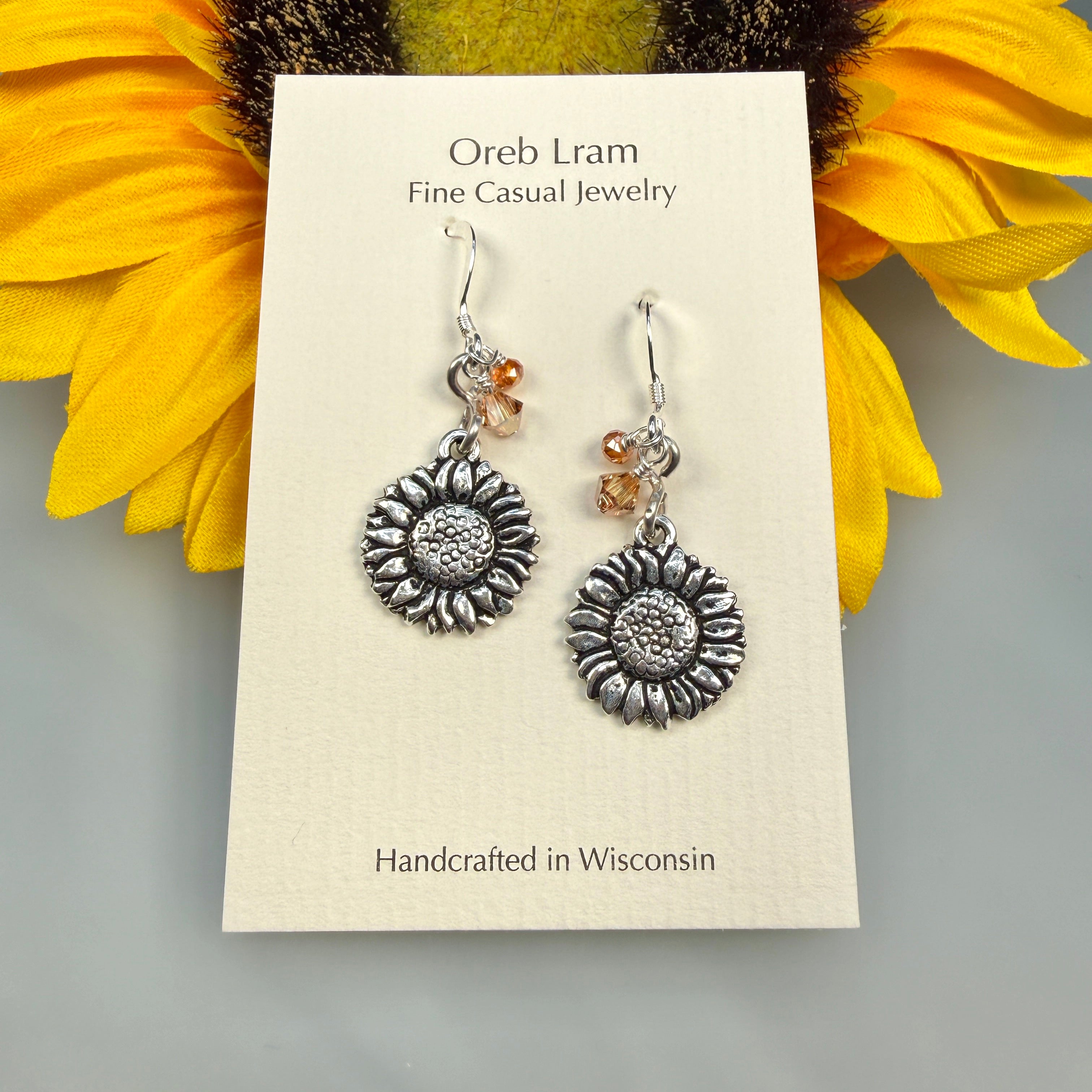 Sunflower earrings on a card with 'Oreb Lram fine casual jewelry branding, set against a yellow sunflower background.