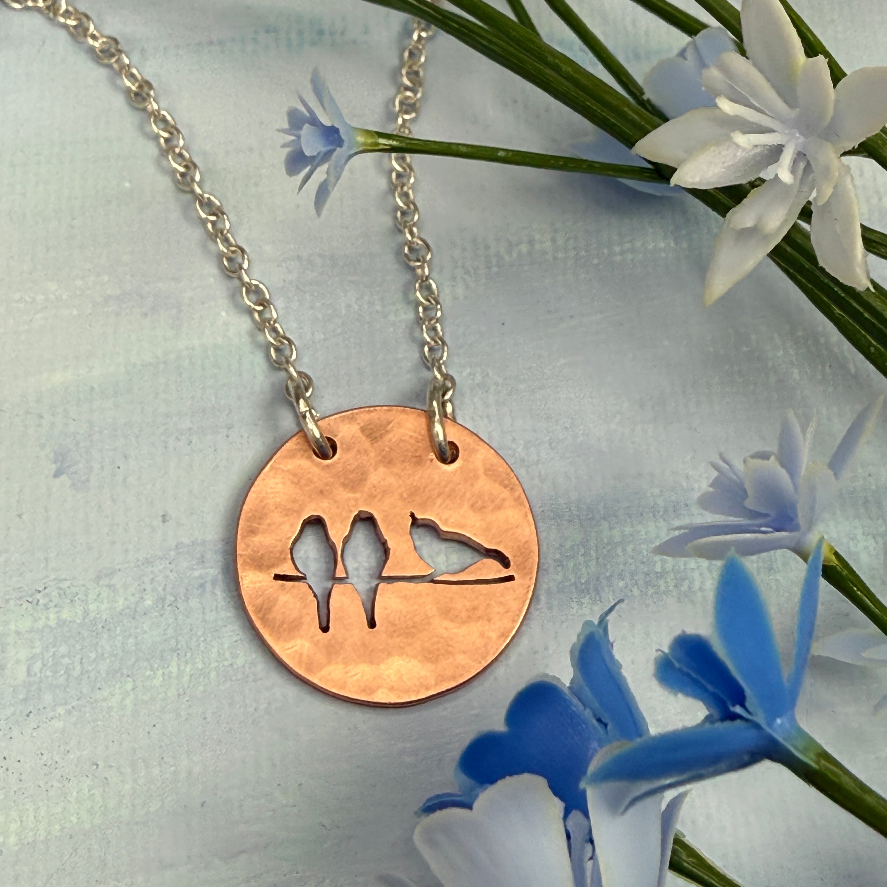 Copper necklace with a silhouette design on a floral background