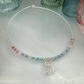 Necklace with multicolored pastel crystal beads and a unicorn charm on a light gray surface.